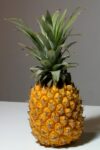 A vibrant composition of a pineapple with coloring pencils and a sketch pad, inspiring creativity.