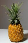 A vibrant composition of a pineapple with coloring pencils and a sketch pad, inspiring creativity.