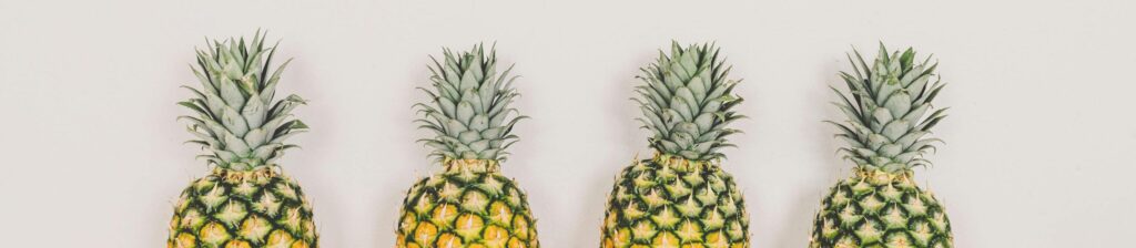 A minimalist image of four pineapples aligned on a white background, perfect for tropical themes.