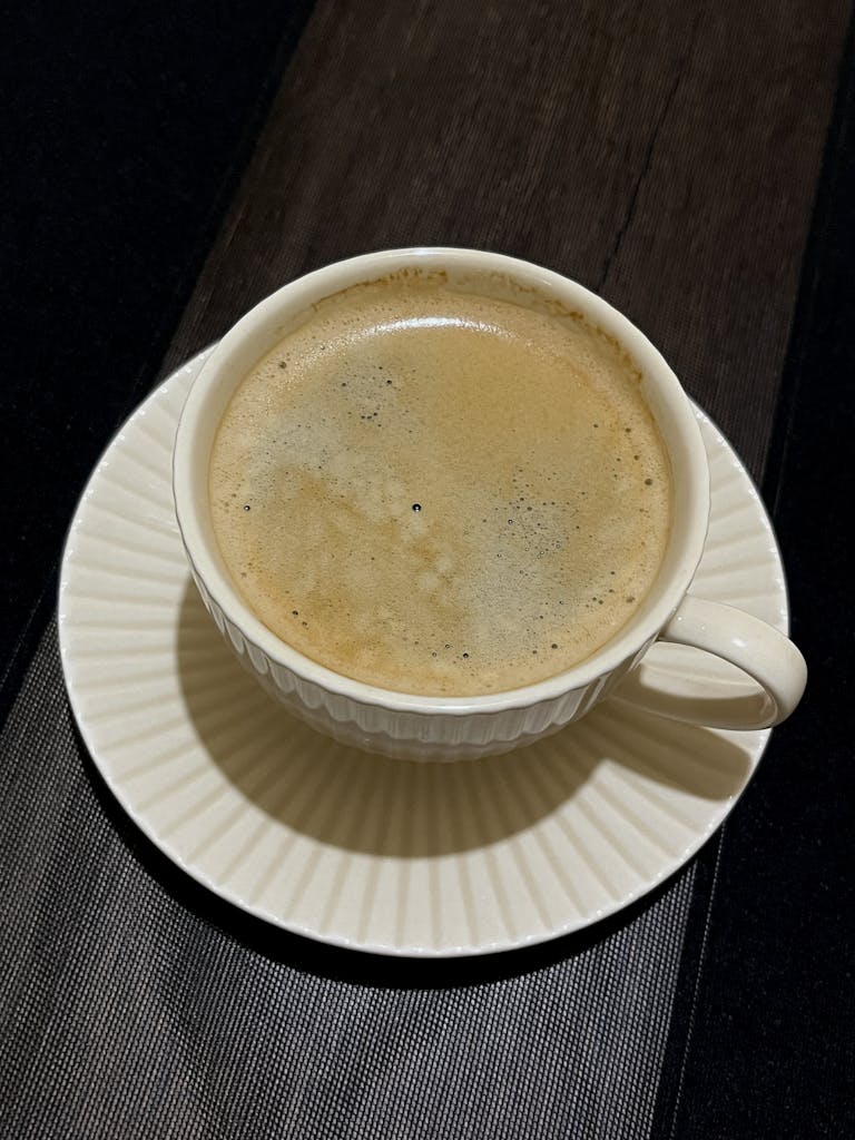 Top view of a hot cup of coffee with foam on a wooden table.