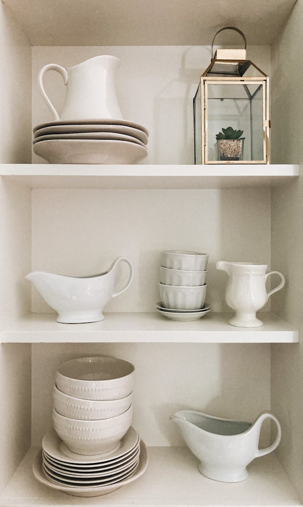 A clean and stylish arrangement of ceramic dishes and teacups on white shelves.