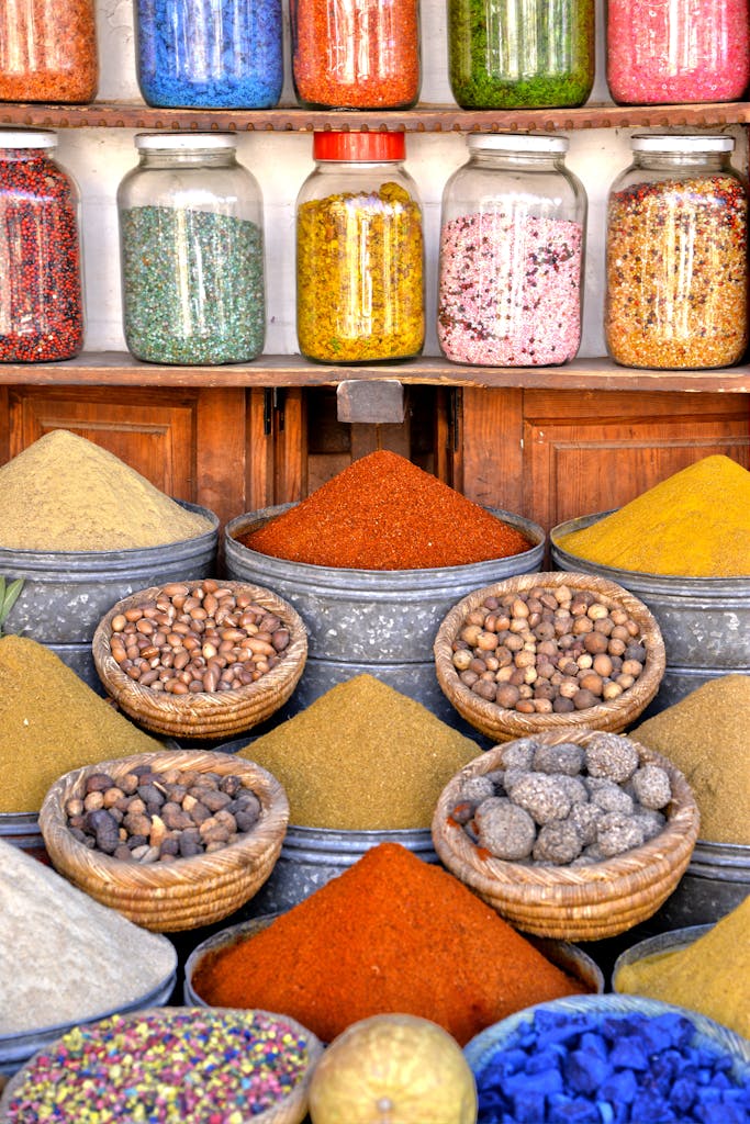 Colorful display of spices and herbs in metal bowls and glass jars at a Moroccan market stall.