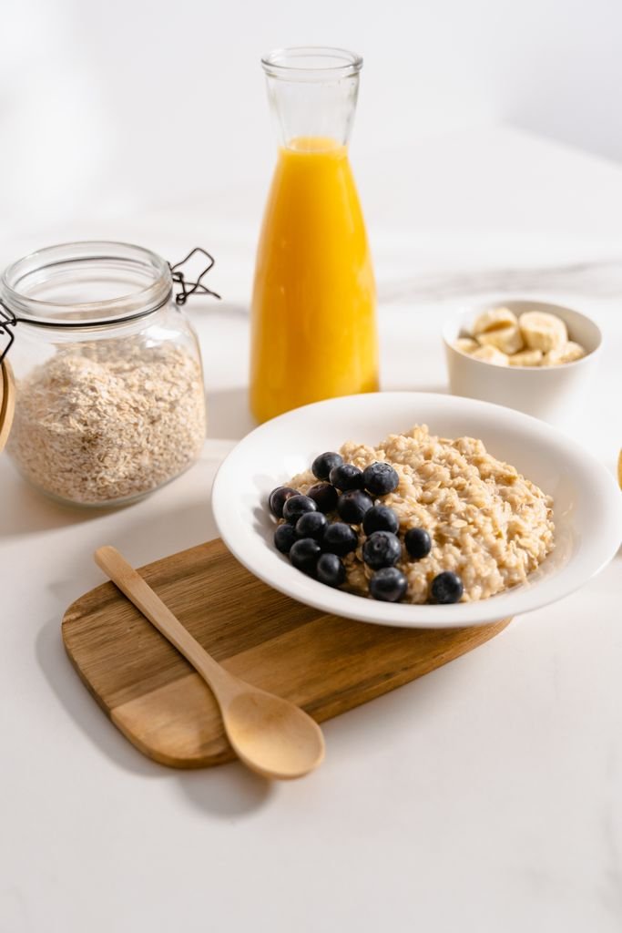 Nutritious breakfast setting with oatmeal, blueberries, and fresh juice on a wooden tray.